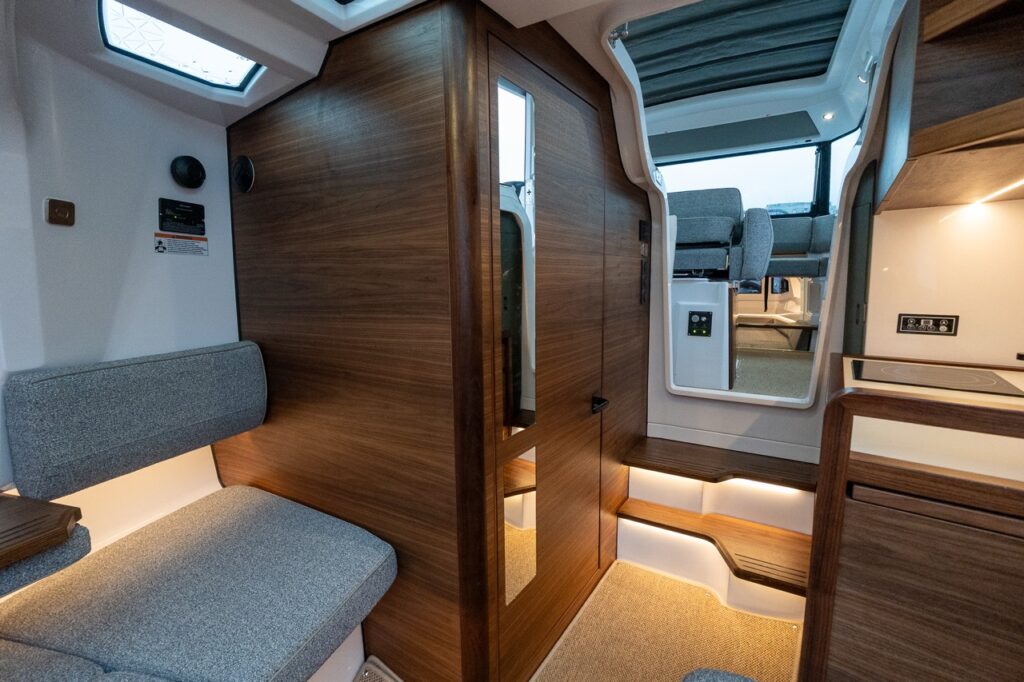 Axopar 38 forward cabin showing elevated seating, warm Nordic wood cabinetry, integrated steps to the pilothouse, skylights, and increased headroom compared to the Axopar 37 and 45.