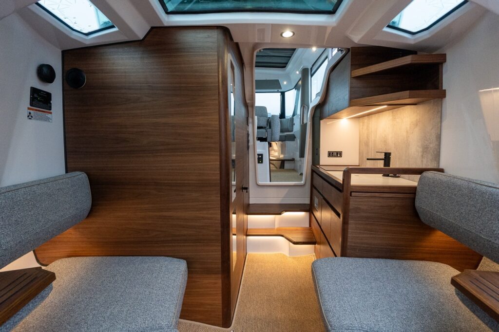 Axopar 38 forward cabin interior showing elevated seating, warmer Nordic wood finishes, integrated galley, skylights, and increased natural light compared to the Axopar 37 and 45.