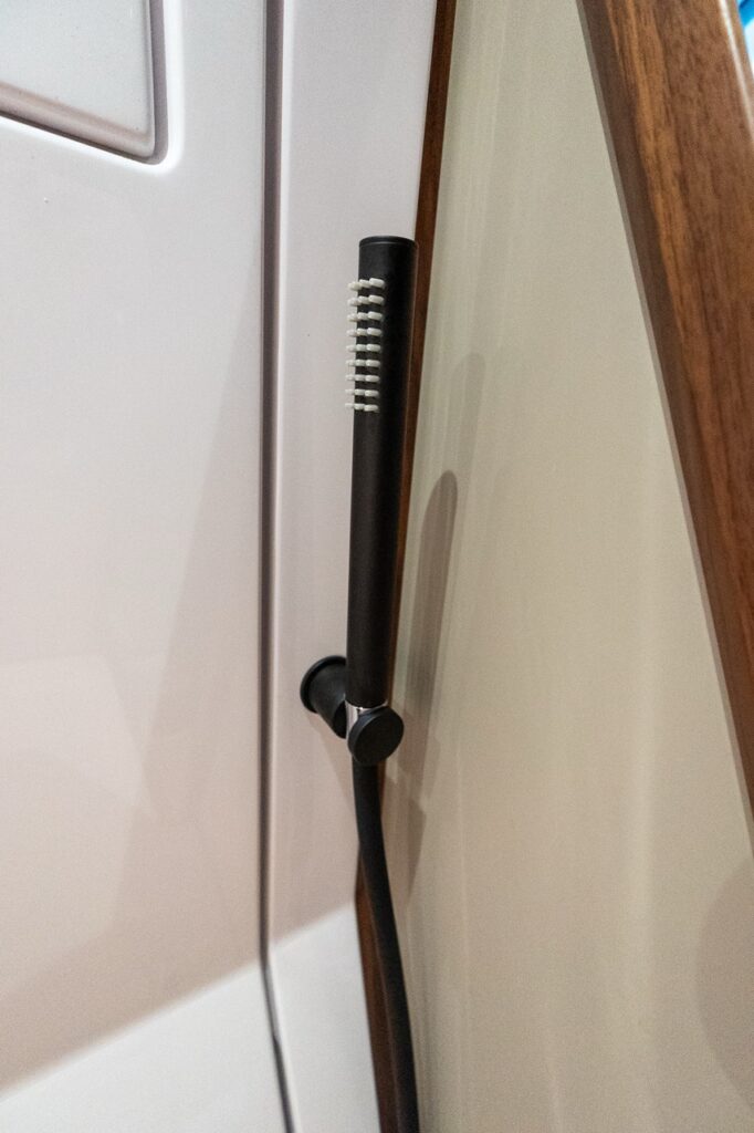 Matte black shower head inside the separate head compartment of the Axopar 38 forward cabin, showing modern fixtures and enclosed wet head design.