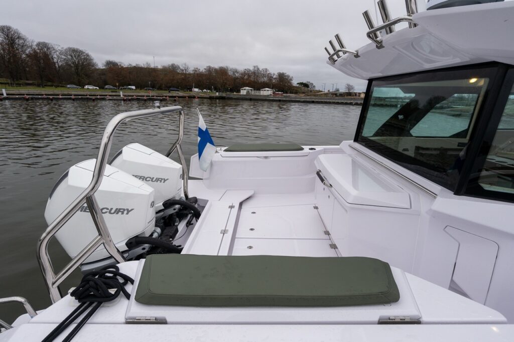 Axopar 38 aft deck with twin Mercury outboard engines, aft wet bar module, and open working cockpit area behind the pilot house.