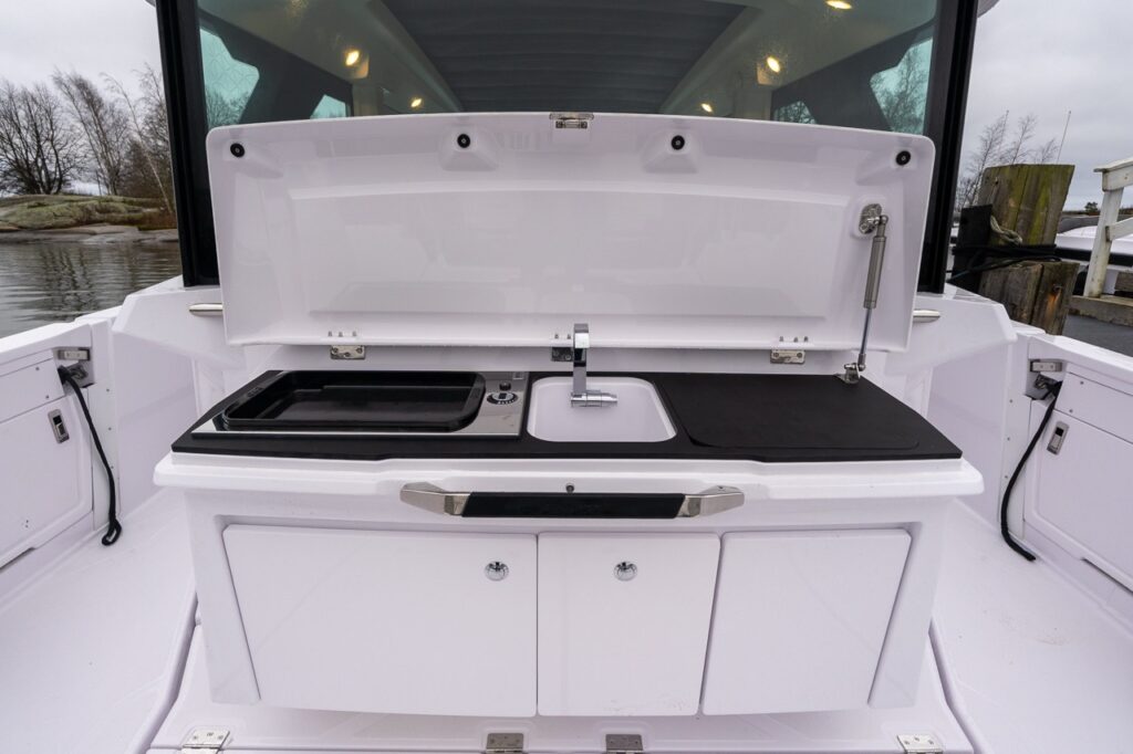 Axopar 38 aft wet bar open behind the pilot house with integrated sink, faucet, cooktop, and prep surface creating a functional outdoor galley.