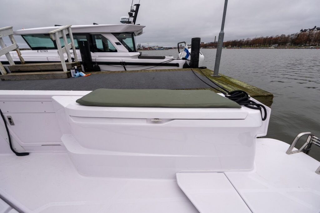 Axopar 38 fenderbox on deck with hunter green cushion, showing integrated storage and seating along the side deck.