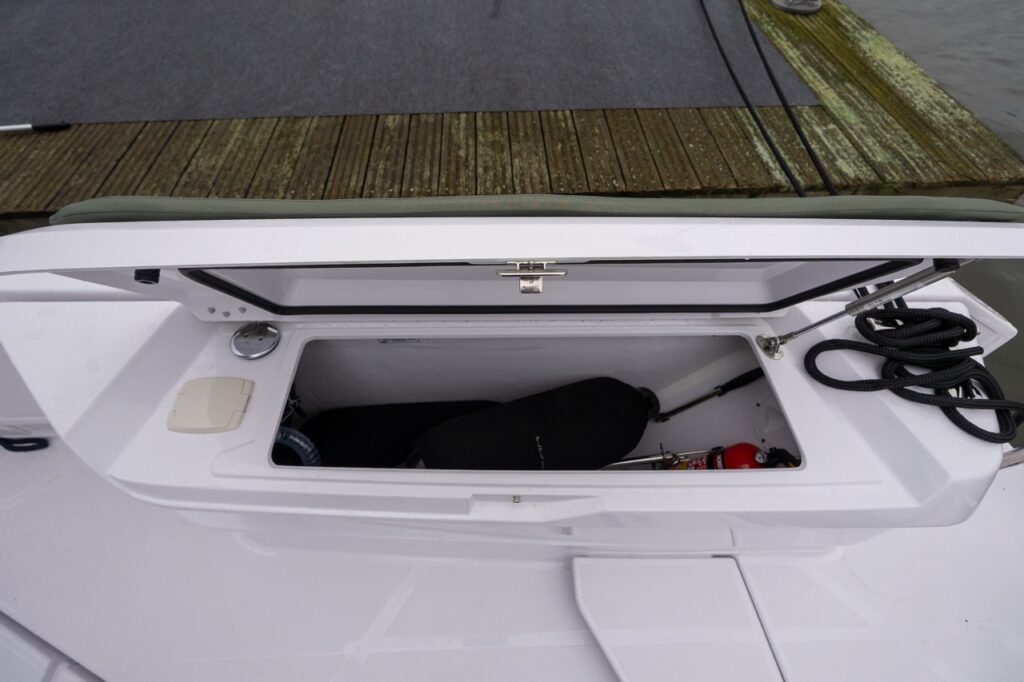Axopar 38 fenderbox storage compartment open, showing integrated fender storage inside the forward fenderbox.