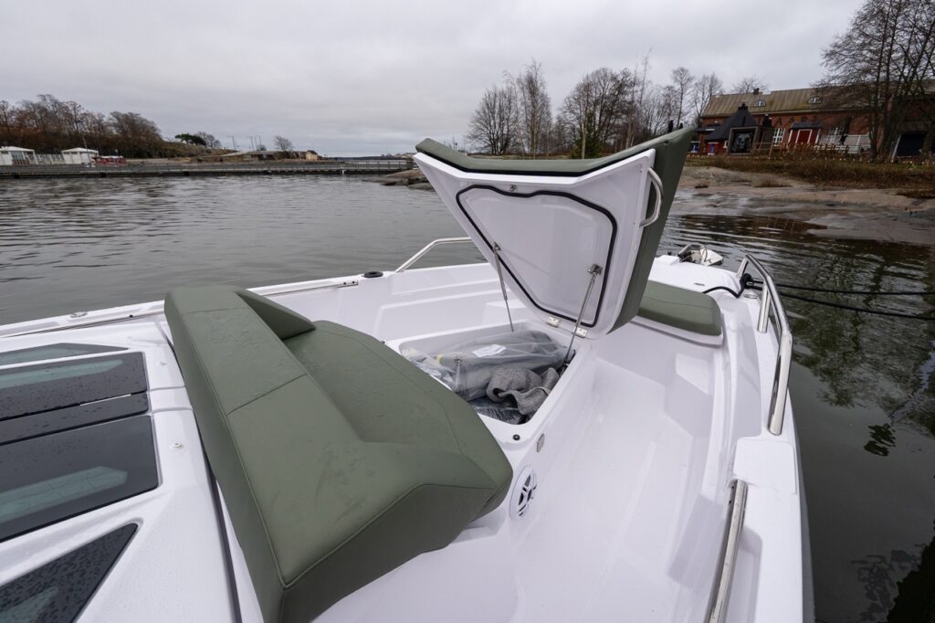 Axopar 38 forward sunbed lifted to reveal integrated bow storage compartment beneath the hunter green cushions during Axopar 38 media day in Finland.