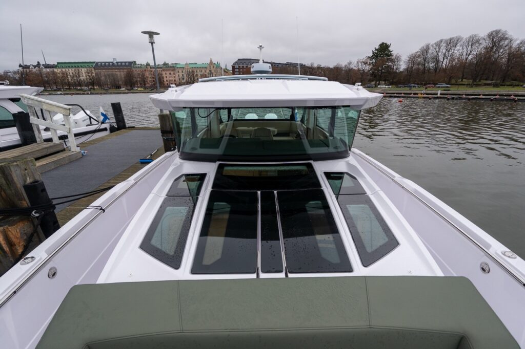 Axopar 38 powerboat viewed looking aft over the forward cabin roof, showing large roof windows, hunter green exterior upholstery, and the pilot house during Axopar 38 media day in Finland.