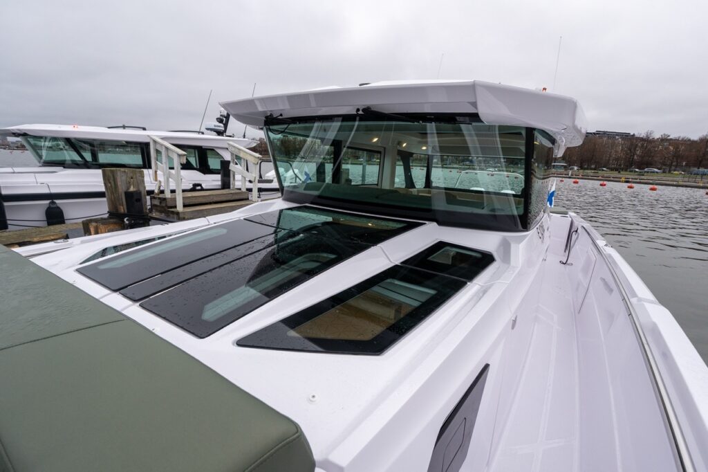 Axopar 38 with hunter green exterior upholstery, viewed looking aft over the forward cabin roof toward the pilot house.