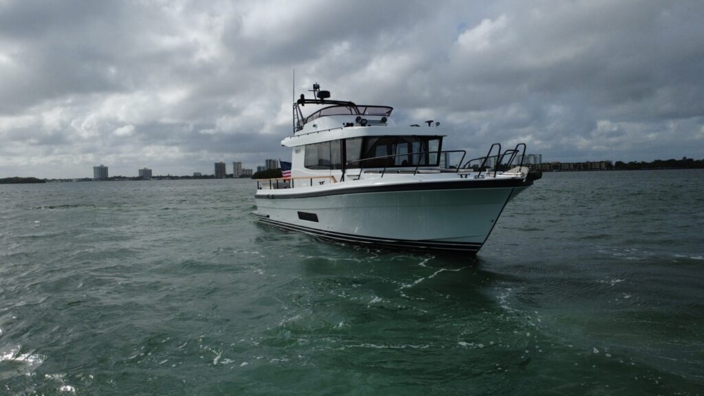 Targa 41 cruising in Florida waters from a forward starboard angle, showing the bow, enclosed pilothouse, flybridge, and walkaround decks.