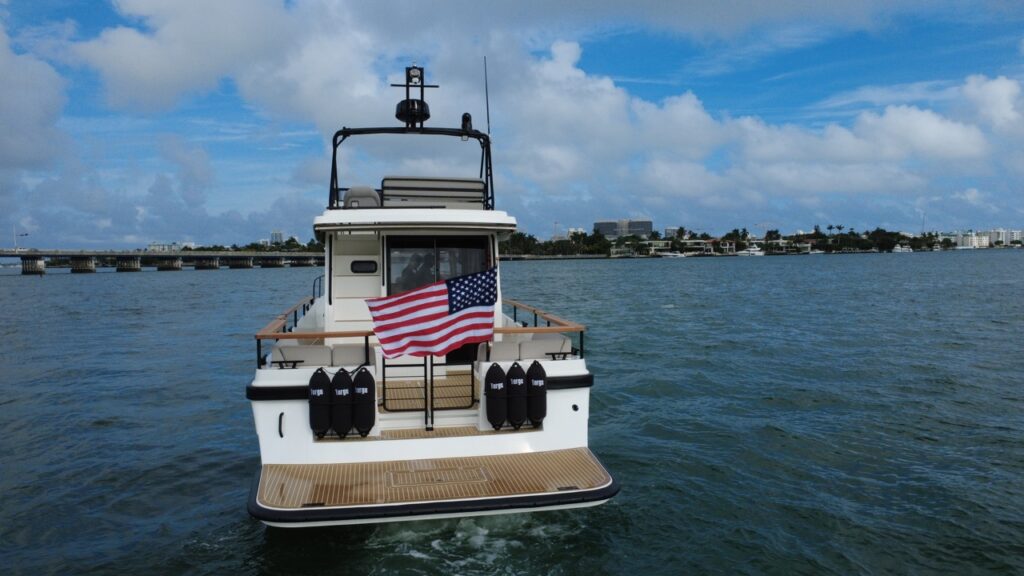Aft view of a Targa 41 underway in Florida, showing the swim platform, cockpit seating, American flag, and flybridge above the pilothouse.