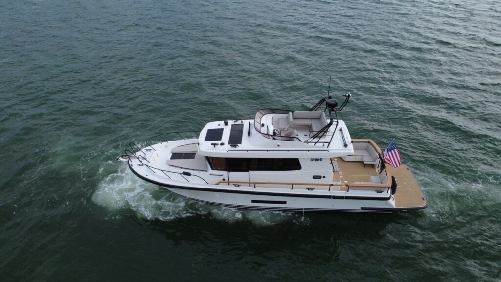 Aerial view of a Targa 41 cruising in Florida waters, showing the flybridge seating area, walkaround decks, aft cockpit, and extended swim platform with U.S. flag.