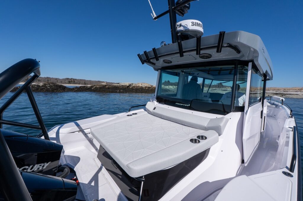 Axopar 29 aft deck sunbed with Chalk upholstery behind the pilothouse and twin Mercury outboards