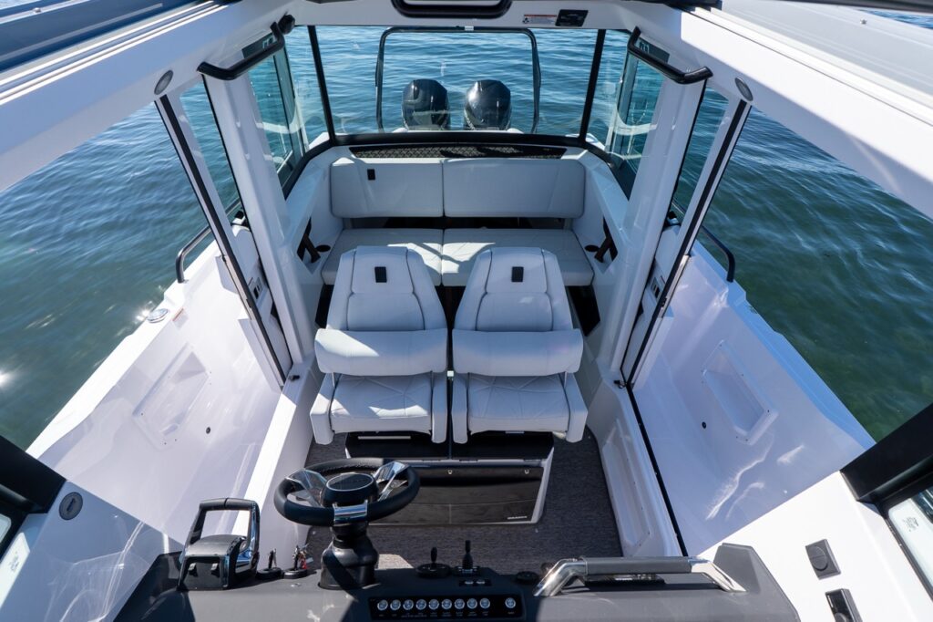 Axopar 29 XC Cross Cabin pilothouse interior viewed from the helm looking aft with twin helm seats and aft bench seating