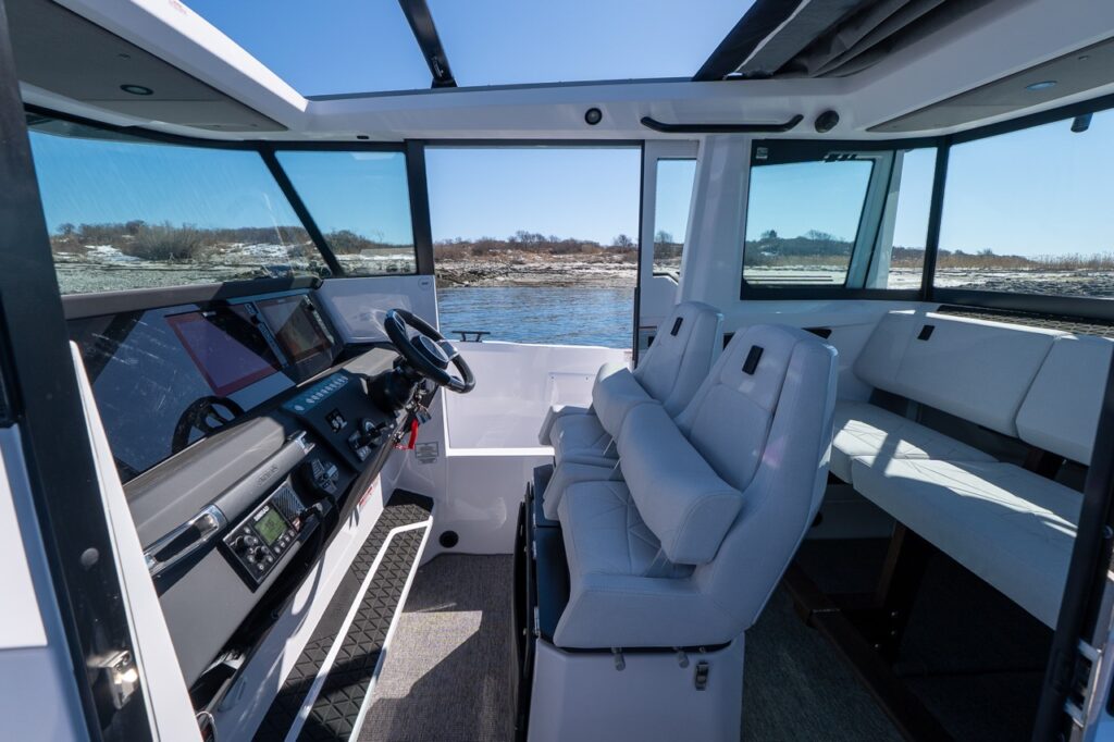 Axopar 29 XC Cross Cabin pilothouse interior with helm dashboard, twin helm seats, and aft seating area
