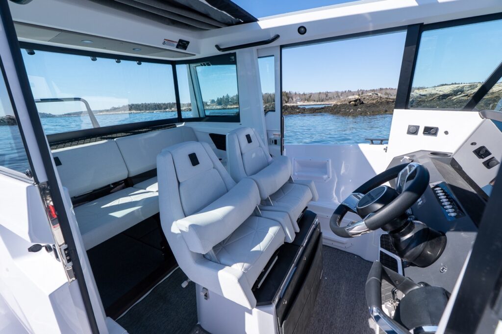 Axopar 29 XC Cross Cabin pilothouse interior with twin helm seats, sliding door, and aft seating area