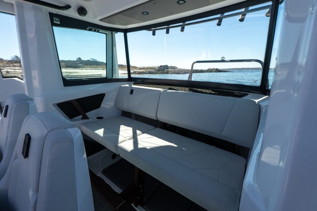 Axopar 29 XC Cross Cabin pilothouse aft seating with large windows and coastal water view