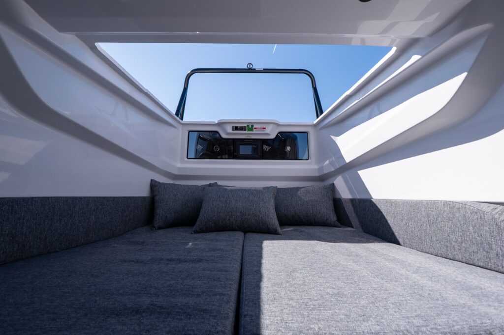 Axopar 29 aft cabin with cushioned berth and open hatch providing natural light and ventilation