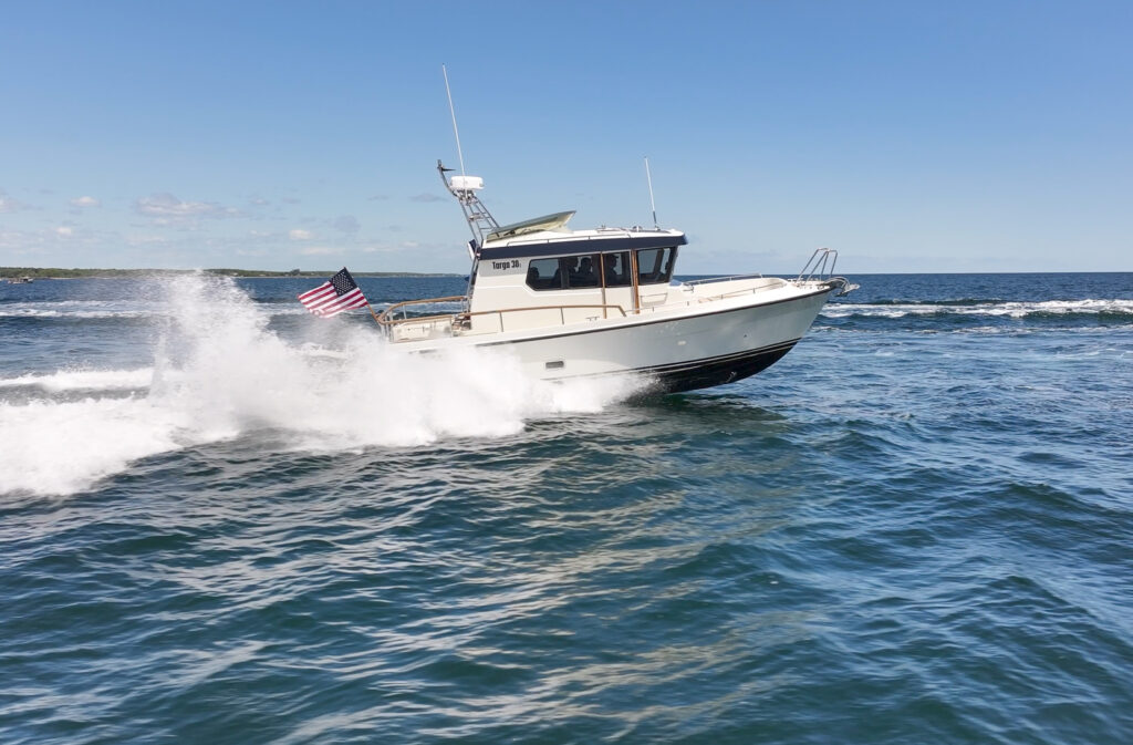 Targa 30.1 pilothouse boat running at speed offshore with spray and American flag