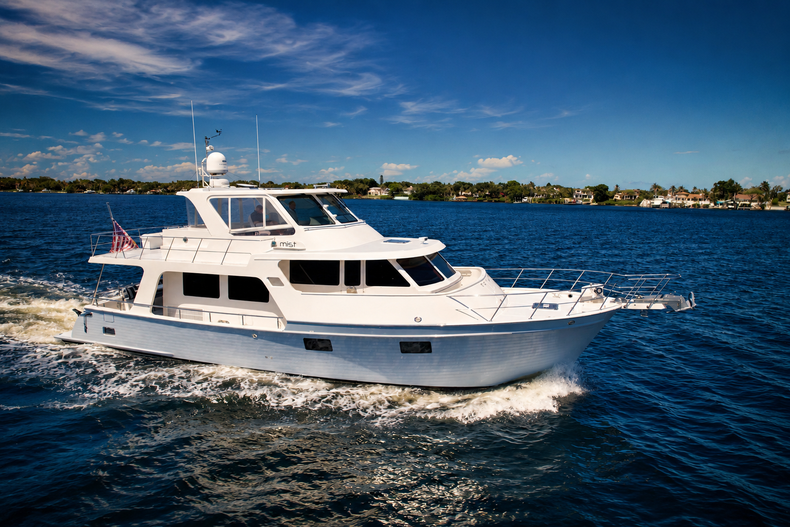 The 2018 Marlow 53E Mist cruises across calm coastal waters, highlighting her semi-enclosed flybridge, gray hull, and efficient owner-operated cruising design.